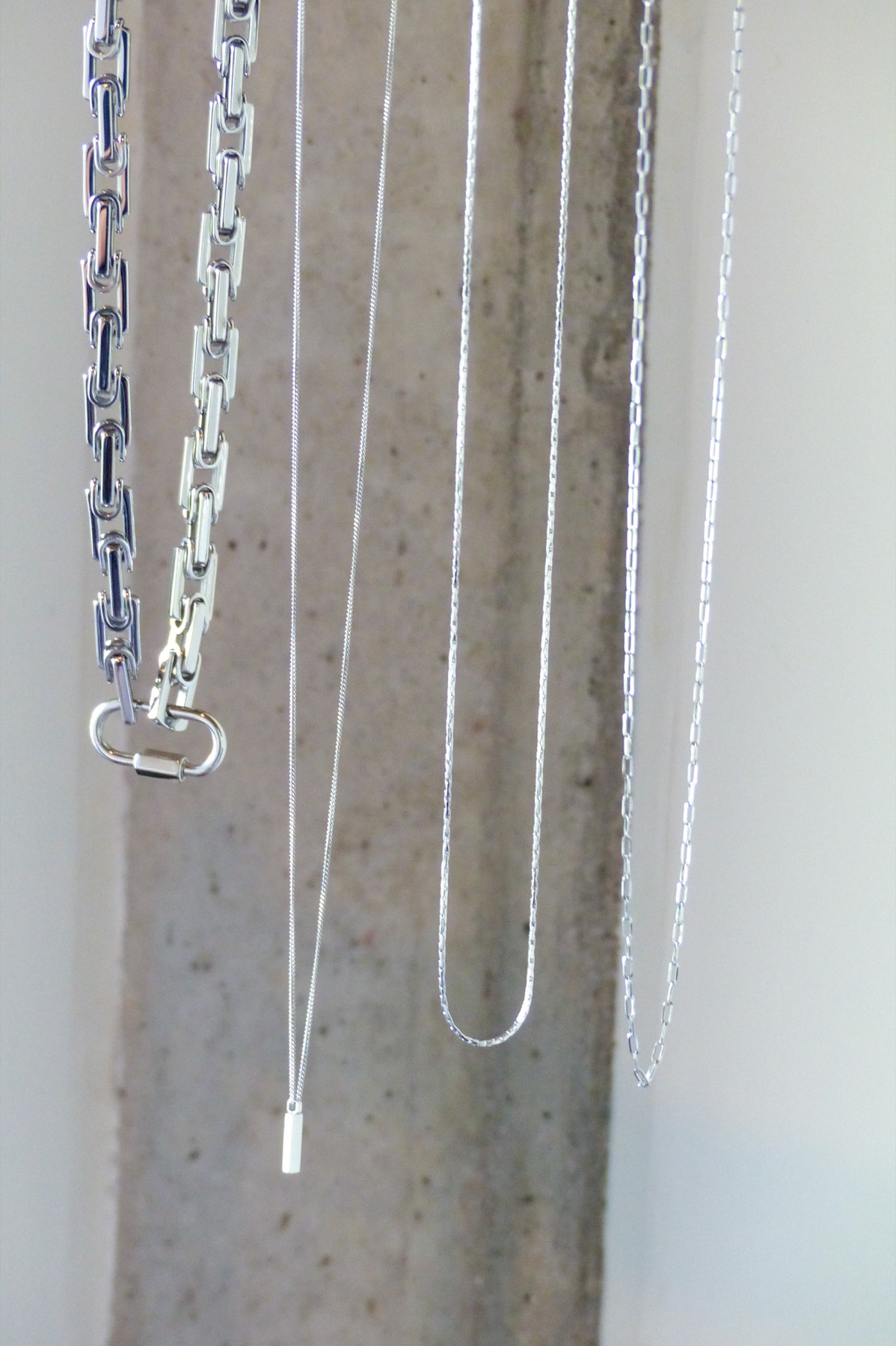 Silver chains hanging against a stone surface